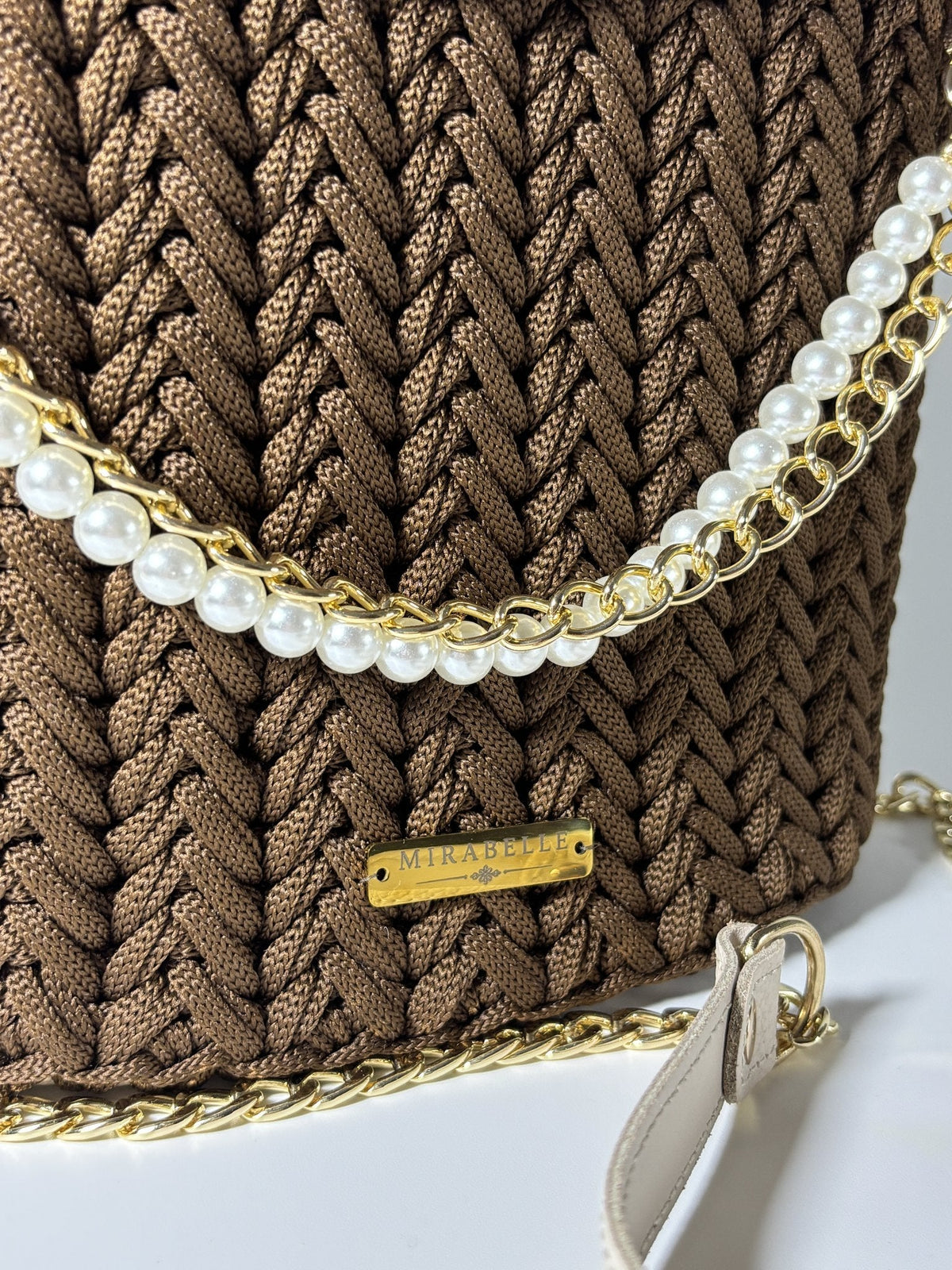 Détail de la chaîne dorée tressée de perles nacrées et de la plaque Mirabelle