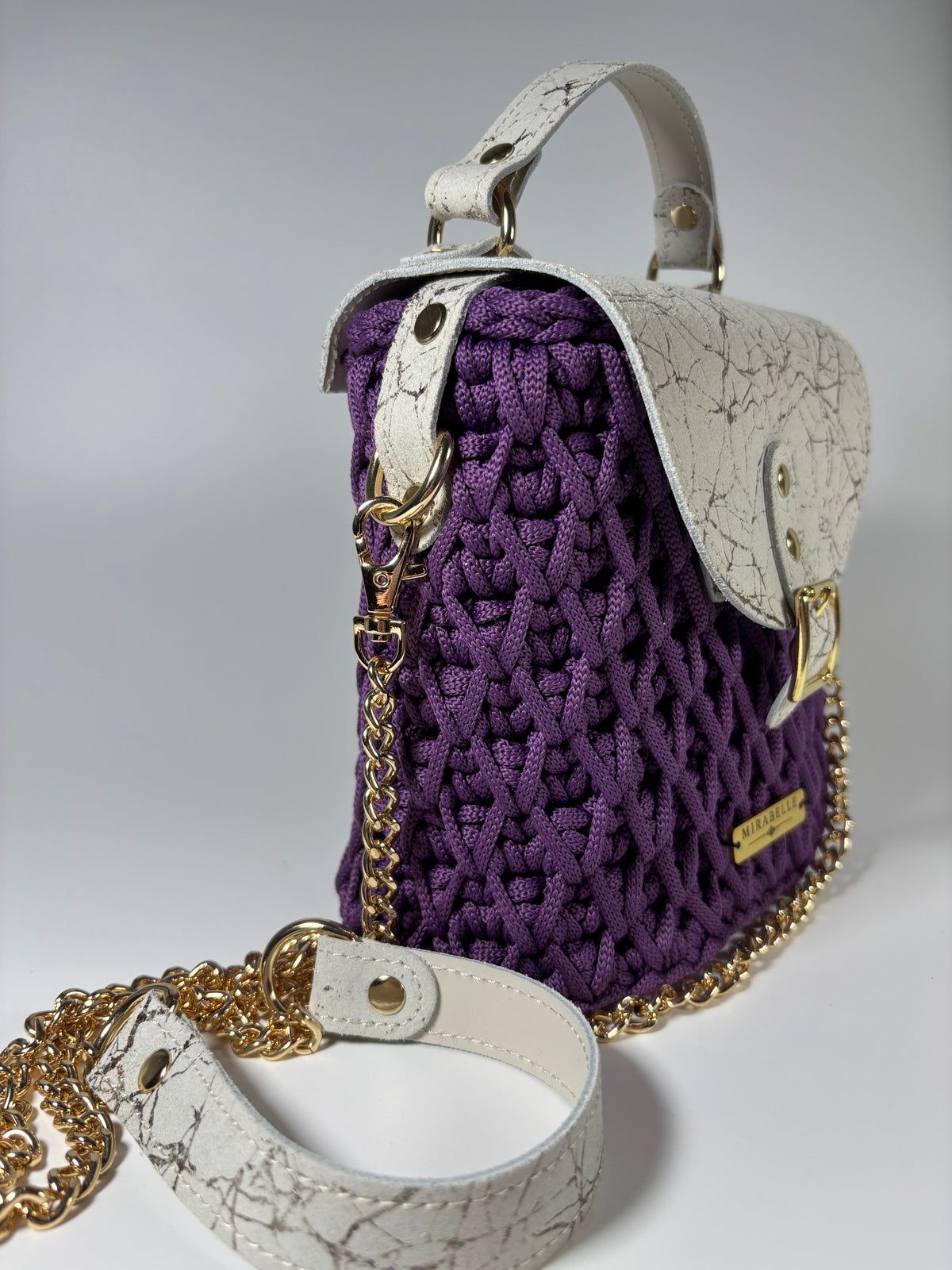 Sac violet vu de côté, anse en cuir blanc et chaîne dorée