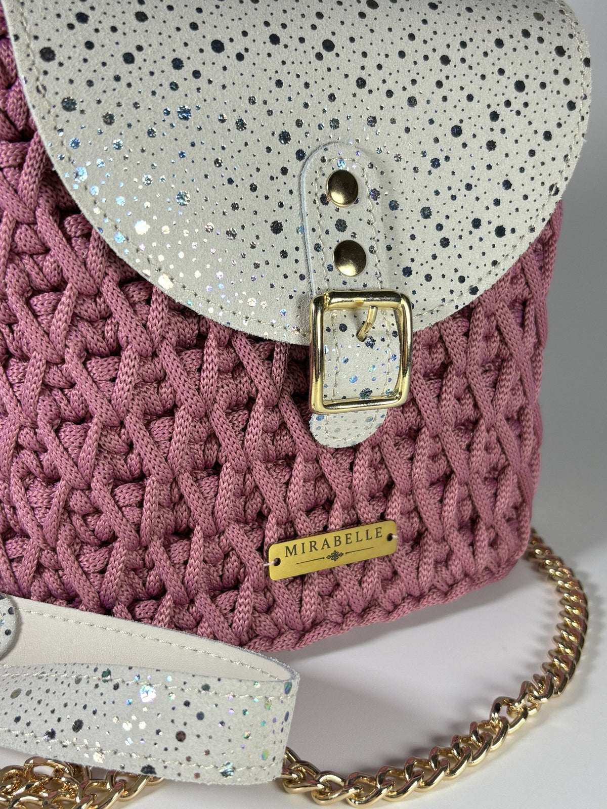 Détail du cuir blanc moucheté argent et de la plaque Mirabelle en laiton doré